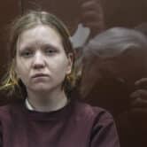 Darya Trepova sits behind a glass cage in a Russian courtroom.