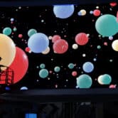 Green, blue, red and yellow balls are shown on a large screen.