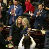 Jennifer Canady and Jenna Persons-Mulicka hug as other lawmakers applaud inside the Florida Capitol.