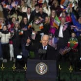 Dozens of people hold American and Irish flags behind Joe Biden as he gives a speech in Ireland.