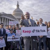 Jamaal Bowman gestures while giving a speech in front of the U.S. Capitol, with several people standing around him holding signs supporting TikTok.