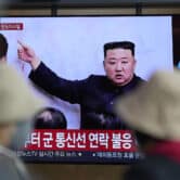People watch a TV screen displaying a South Korean news program showing a file image of Kim Jong Un.