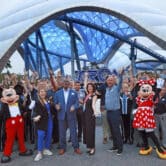 People wearing Mickey and Minnie costumes stand near Magic Kingdom employees at the opening ceremony for a Tron-related attraction.