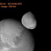 A black and white image of Mars and its moon Deimos.