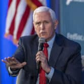 Mike Pence holds a microphone while speaking on stage an event.