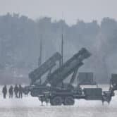 People stand near Patriot missile launchers in a field in Poland.