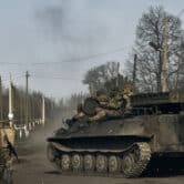 Several Ukrainian soldiers ride atop a tank in Bakhmut, Ukraine.