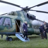 Vladimir Putin exits a military helicopter with three people standing nearby.