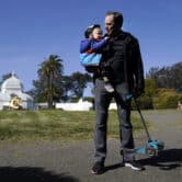 Zack Rosen holds his daughter in front of the Conservatory of Flowers in San Francisco's Golden Gate Park.