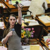 Zooey Zephyr holds a microphone above her head while standing on the Montana House floor.