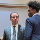 White man in suit looks at black man in suit.