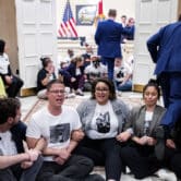 Activists lock arms while staging a sit-in outside Ron DeSantis' governor's office.