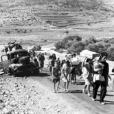 More than a dozen Arab refugees walk along a dirt road in 1948.