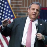 Chris Christie raises his right hand while speaking at an event.