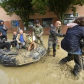 Several people ride on a floatation device through muddy water during a rescue operation in Italy.