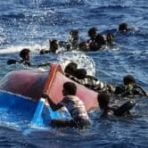 Migrants swim next to an overturned wooden boat off the coast of Italy.