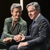 Margrethe Vestager shakes hands with Antony Blinken while speaking on stage during an event.