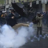 A man kicks in a tear gas canister during a demonstration, Monday, May 1, 2023 in Paris.