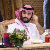 Mohammed bin Salman touches his ear while sitting for a meeting.