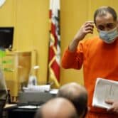 A man in orange sweats in a courtroom.