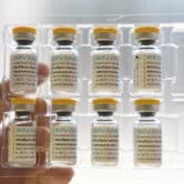A person holds a plastic package containing eight vials of the mpox vaccine.