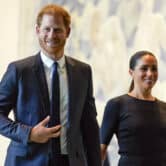 Prince Harry and Meghan Markle smile while walking together.