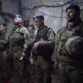 Ukrainian soldiers line up inside a poorly lit building.