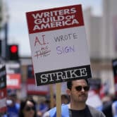 Writers Guild of America members hold signs while picketing outside Fox Studios.