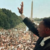 Martin Luther King Jr. raises his arm while giving his "I Have a Dream" speech in front of thousands of people at the Lincoln Memorial.