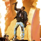 Travis Scott raises a microphone above his head while performing at the Astroworld Music Festival.