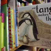 A copy of "And Tango Makes Three" sticks out from a shelf with other books in a store.