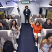 Nine passengers sit in a Brightline train car, while an employee stands in the back.