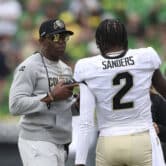 Deion Sanders and Shedeur Sanders talk during a college football game at Autzen Stadium.