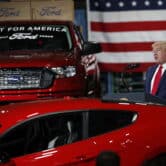 Donald Trump speaks next to a red Ford pick-up truck and a Ford sedan at one of the company's plants.