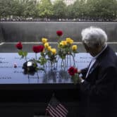 A man places a rose next to other flowers on the 9/11 Memorial in New York.