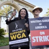 Fran Drescher and Meredith Stiehm hold SAG-AFTRA and WGA protest signs outside the Paramount Pictures studio.
