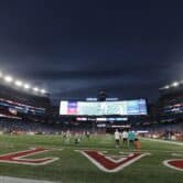 Several people stand on the field at Gillette Stadium before an NFL game.