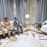 A three-member delegation from Yemen's Houthi rebels meet with a Saudi Arabian official in a room with marble flooring.