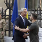 Jens Stoltenberg shakes hands with Volodymyr Zelenskyy outside a building in Kyiv.