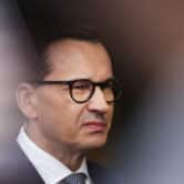 Mateusz Morawiecki wearing dark-rimmed glasses and a suit.