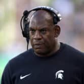 Mel Tucker walks on the field at Michigan State's football stadium while wearing a headset.