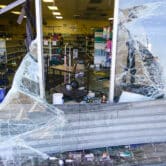 A ransacked liquor store with a several damaged storefront window.