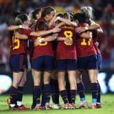 Several players on the Spanish Women's National Team embrace during a group hug during a soccer match.
