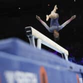 Simone Biles jumps above a beam during a gymnastics competition.