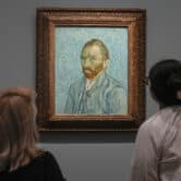 Two people look at a self portrait painted by Vincent van Gogh.