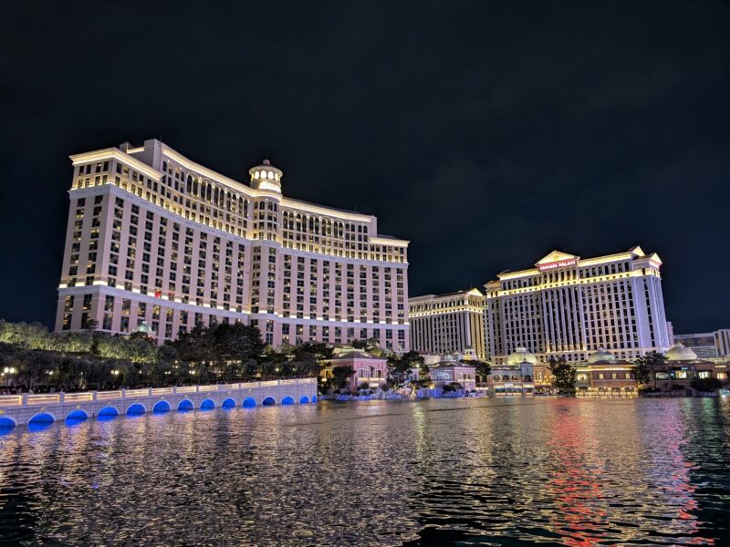 Two large and lighted hotels cast their reflections on a lake.