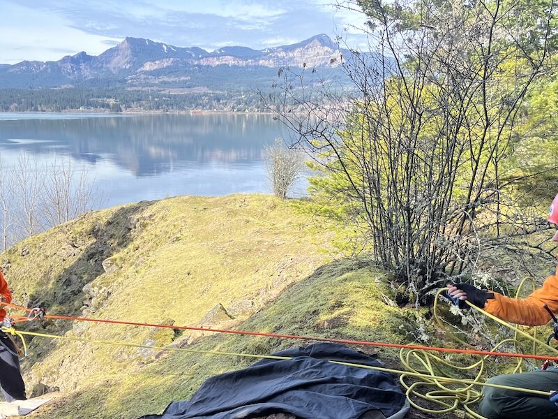A man scales down a hill using ropes.