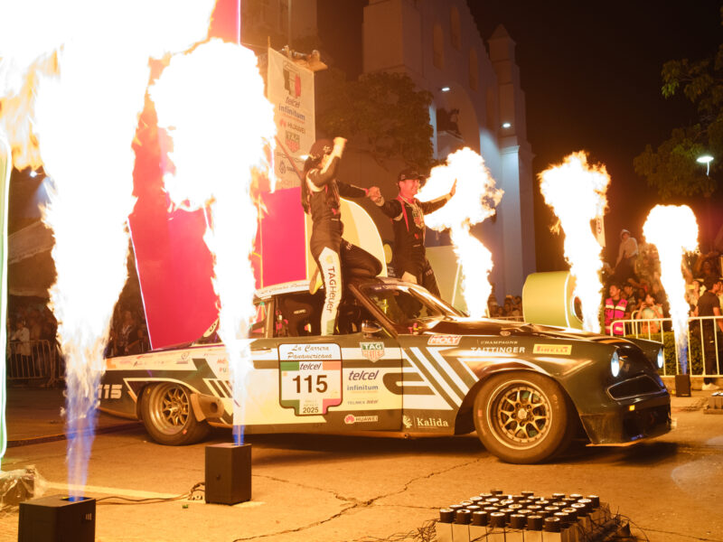 Flames surround a couple standing on their car.