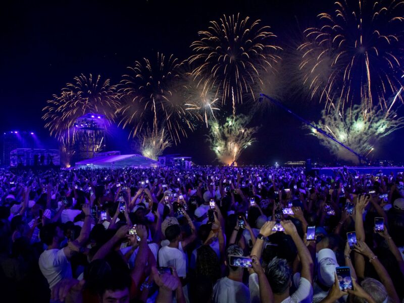 Crowd dressed mostly in white watches fireworks over Copacabana beach during New Year's Eve celebrations in Rio de Janeiro.