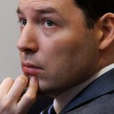 A man in a gray suit looks at something in the distance.